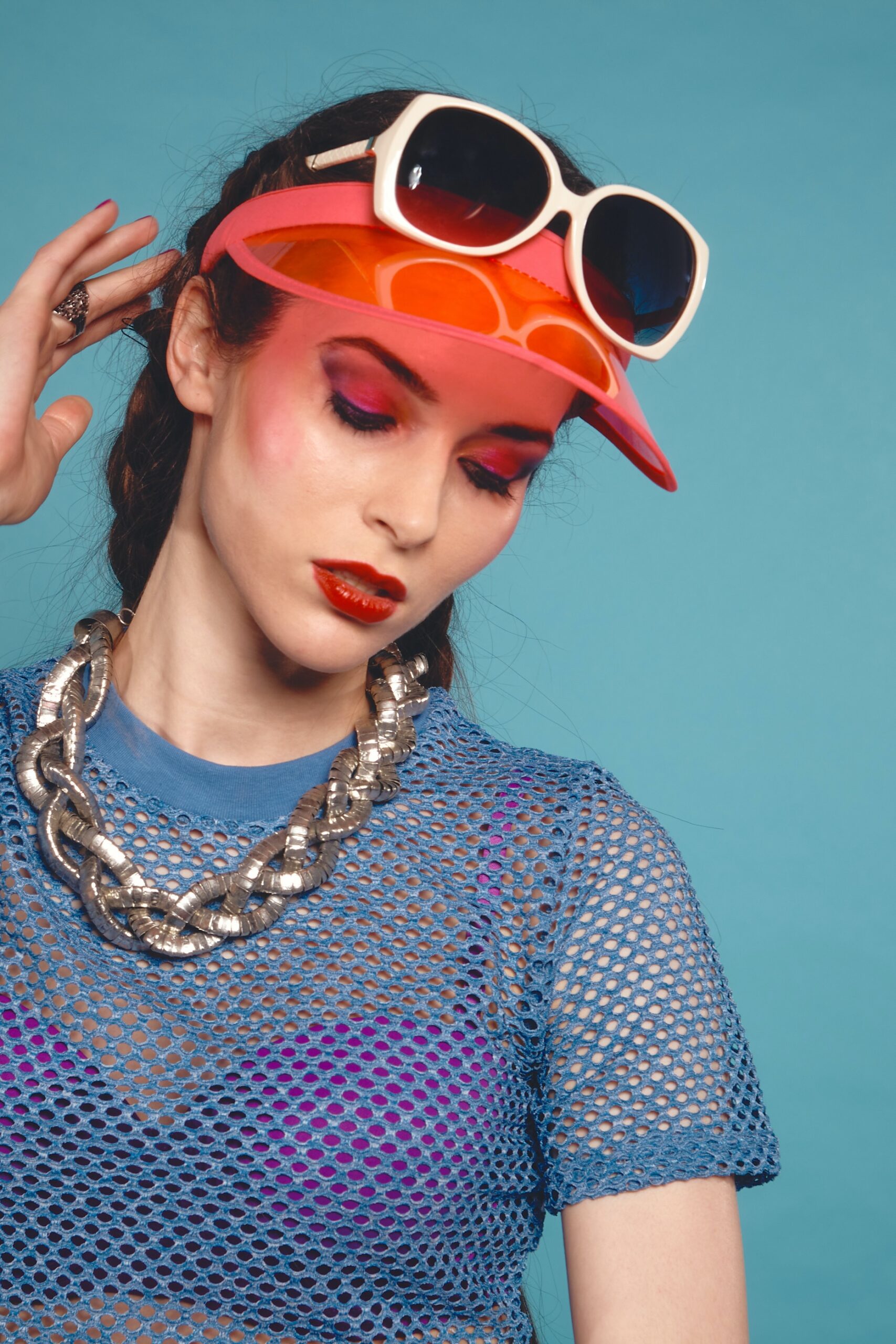 woman in gray knit sweater wearing orange sunglasses and red cap