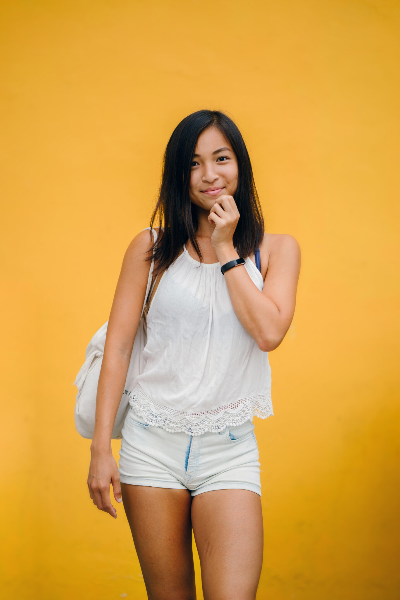 Woman wearing white sleeveless shirt and white denim shorts